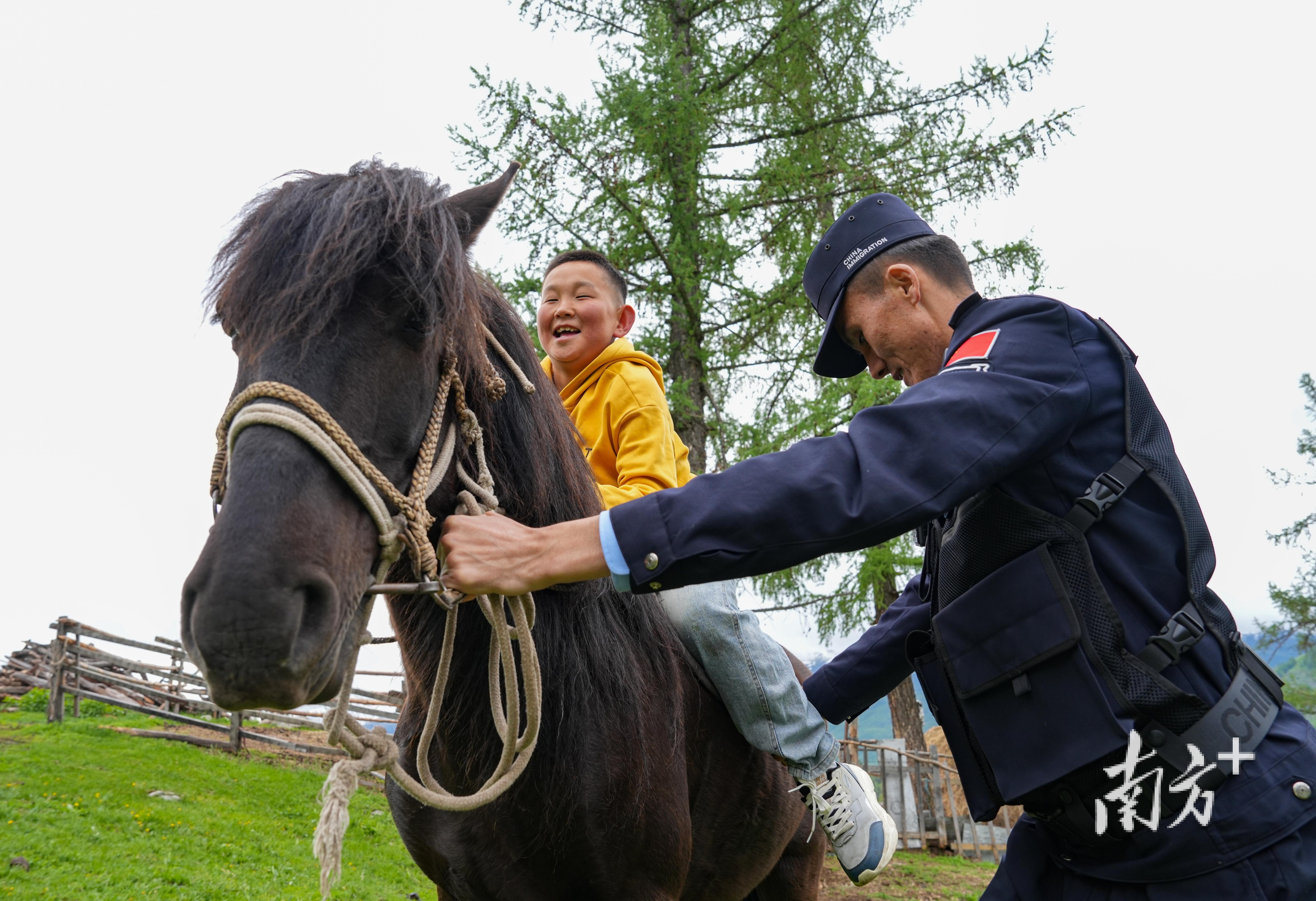 正在入户走访的民警阿依托尔·艾力帮助牧民家的孩子上马。